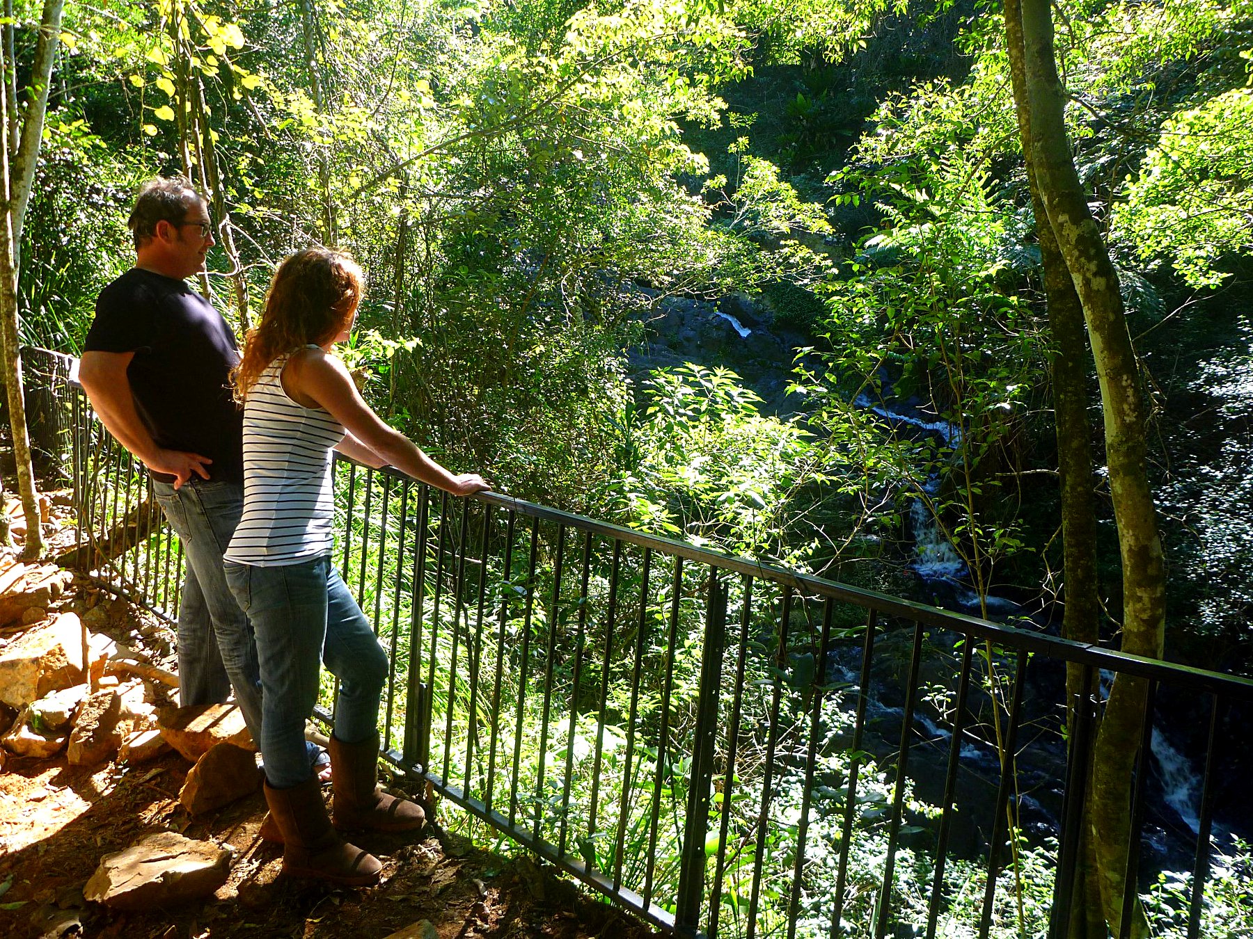 Two guests at a railing on the viewing platform looking down at a cascade